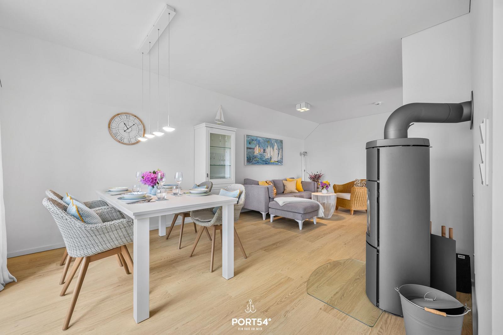 Essbereich mit Tisch und Stühlen, Wohnbereich mit Sofa und Kaminofen.