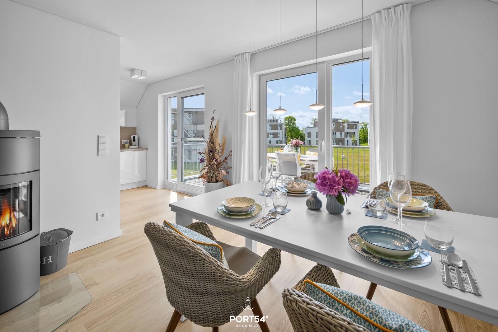 Esstisch mit Stühlen, Kamin und Blick auf Balkon