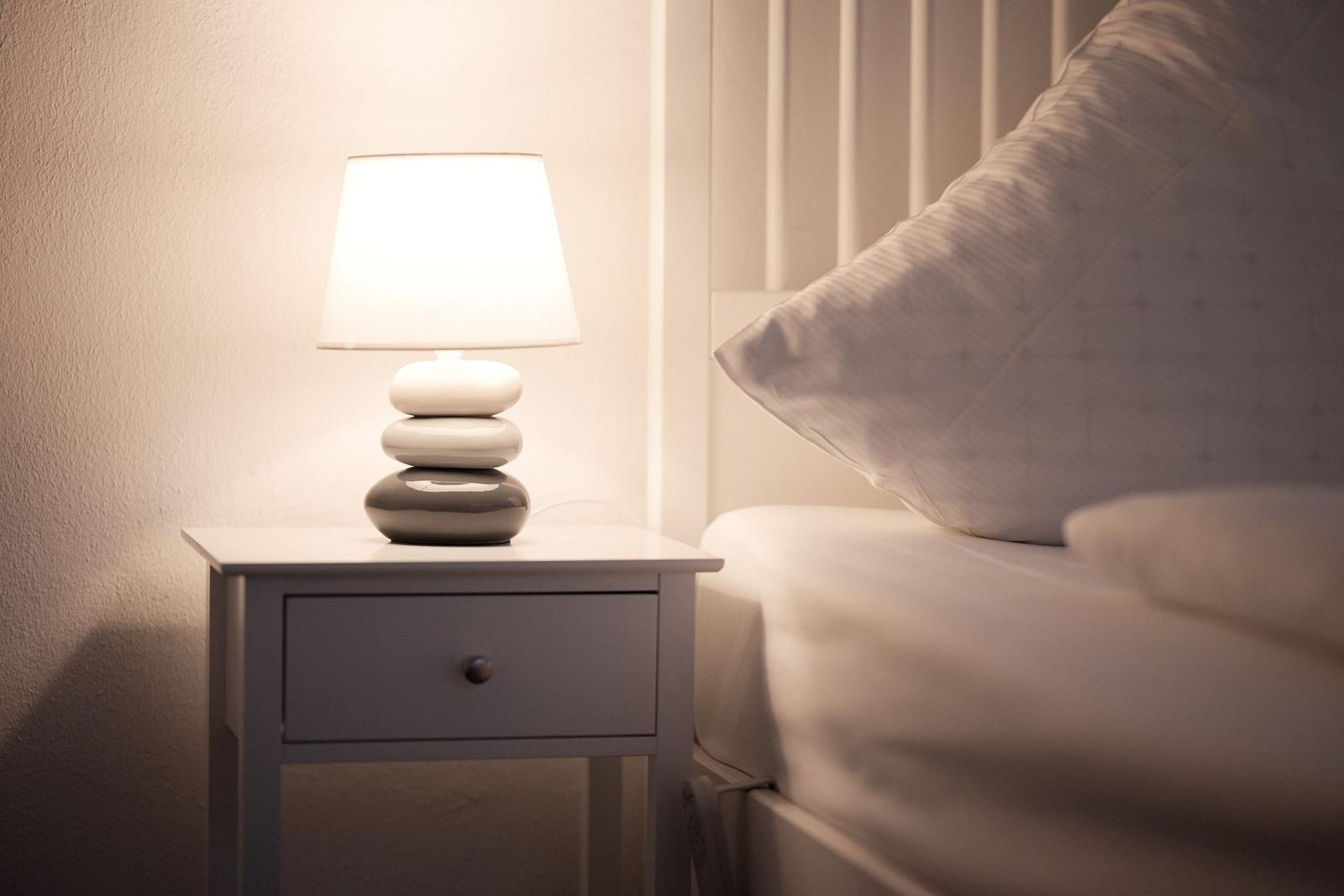 Schlafzimmer mit Nachttisch und Lampe neben Bett