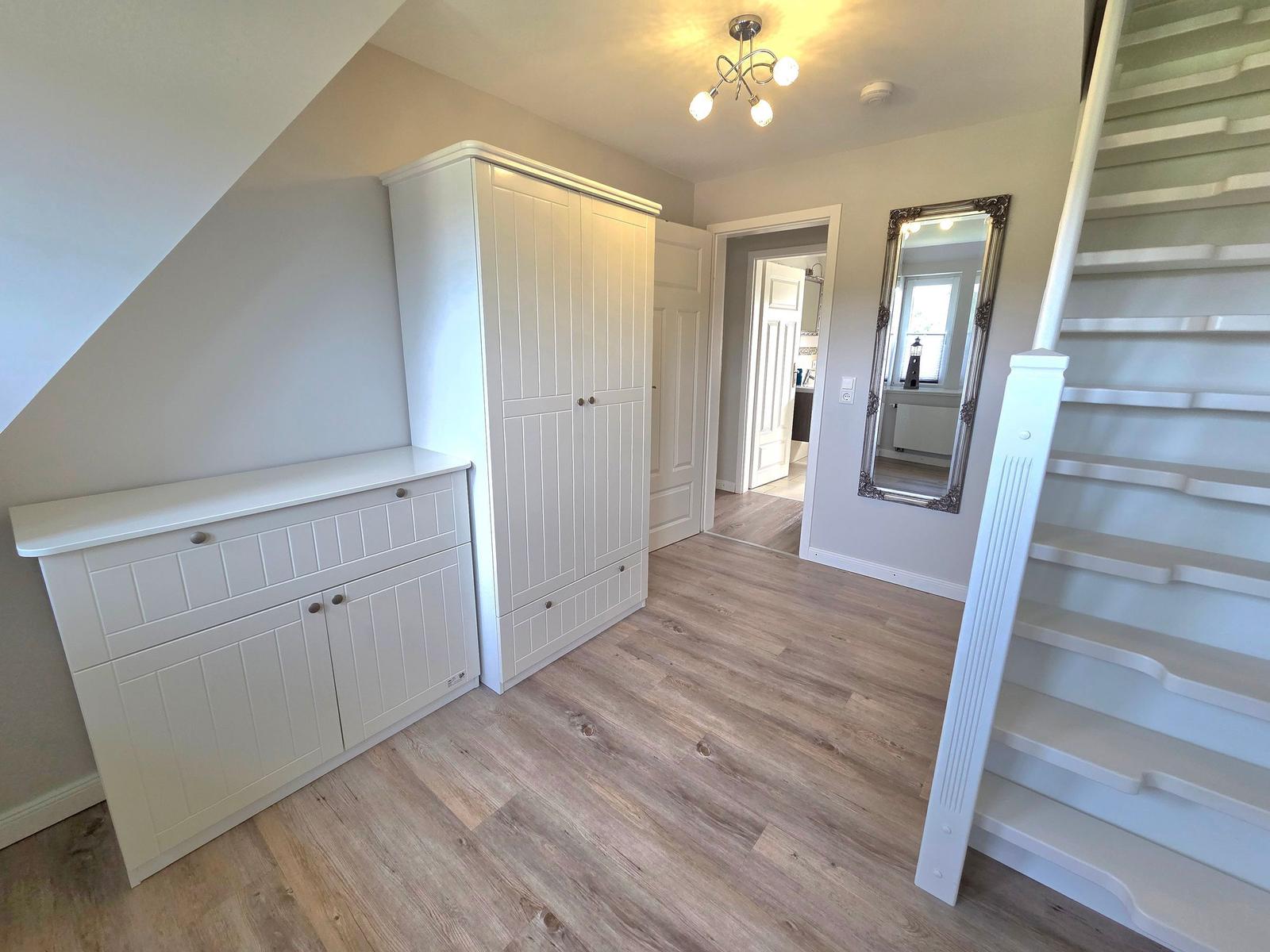 Living area with white cabinets, wooden floor, and staircase to upper level.