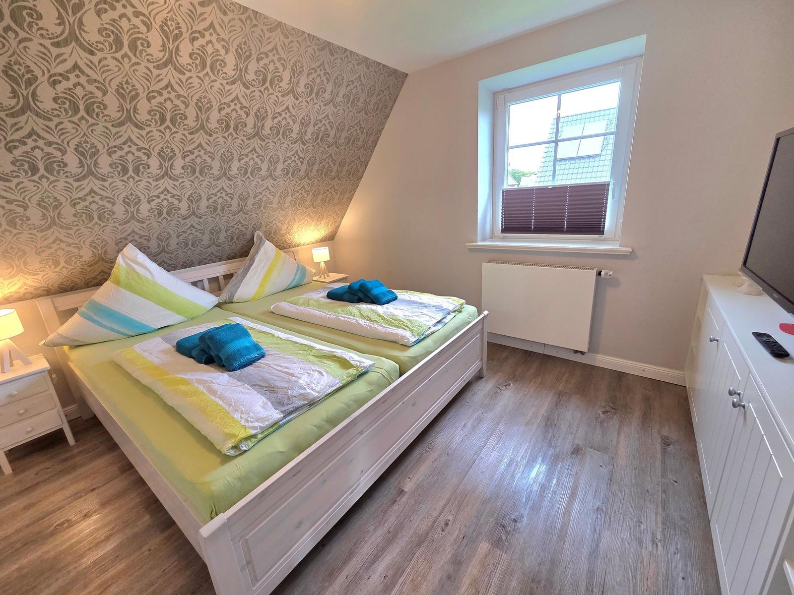 Bedroom with double bed, window, and TV cabinet.
