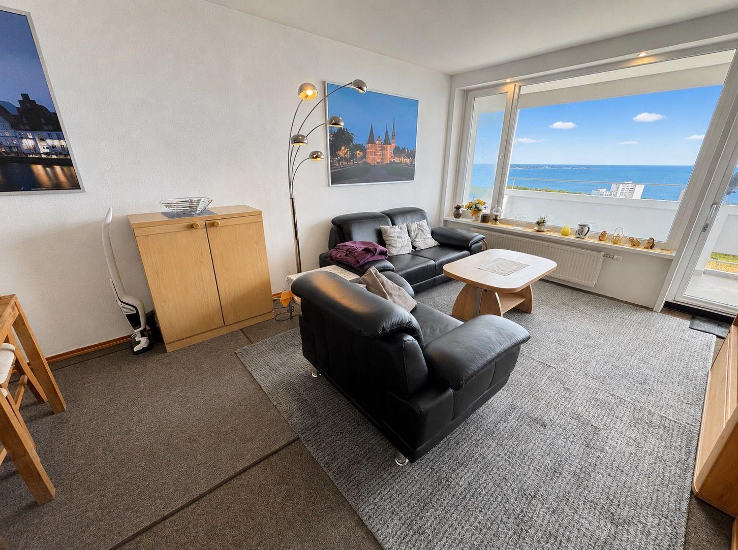 Wohnzimmer mit Sofa, Sessel und Blick aufs Meer.