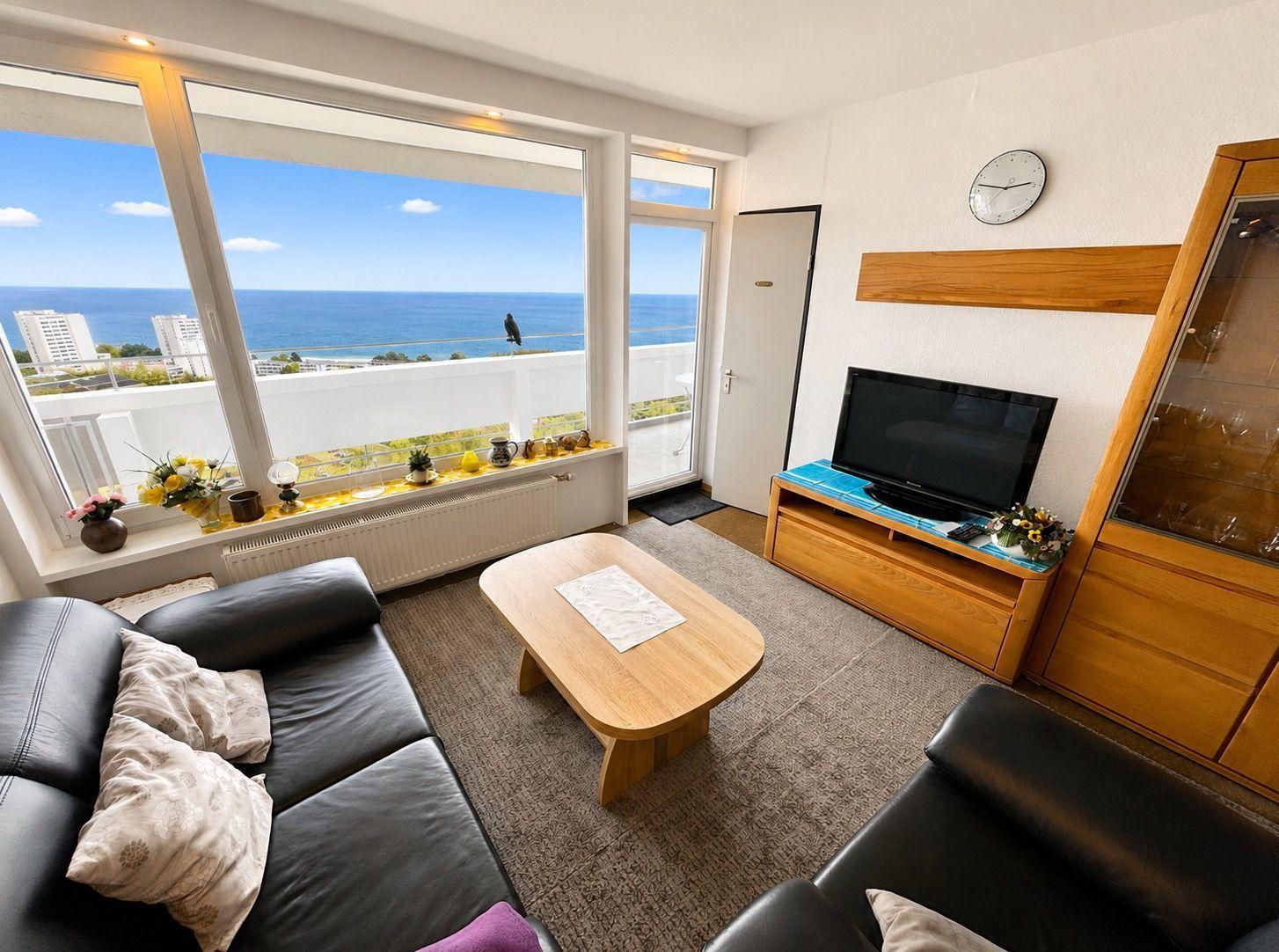 Wohnzimmer mit Blick aufs Meer, Sofa, Couchtisch und Fernseher.