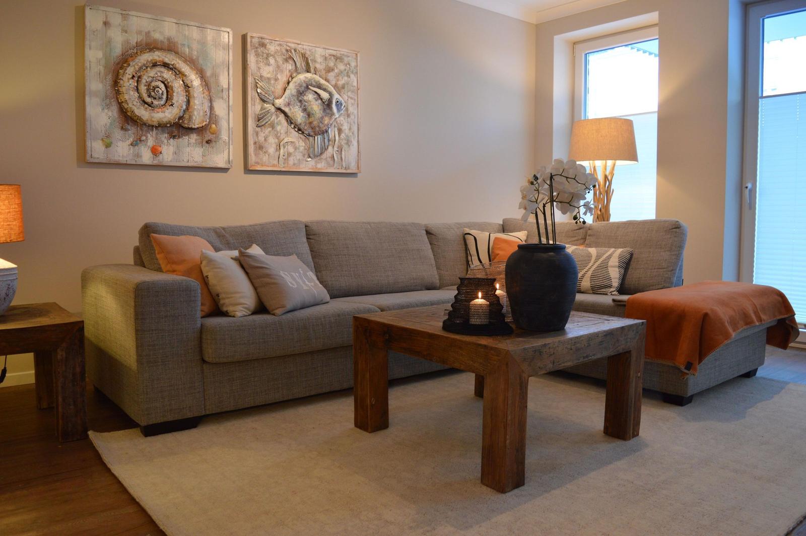 Ein Wohnzimmer mit grauem Sofa, Holztisch und Wandbildern.