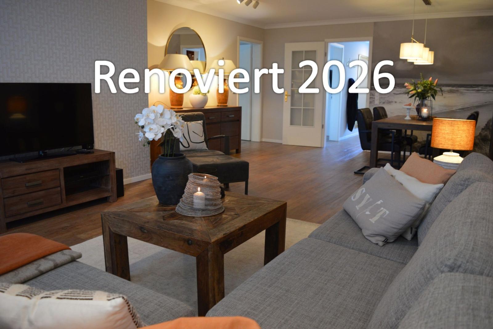 Wohn- und Essbereich mit Sofa, Couchtisch und Fernseher. Renoviert 2026.