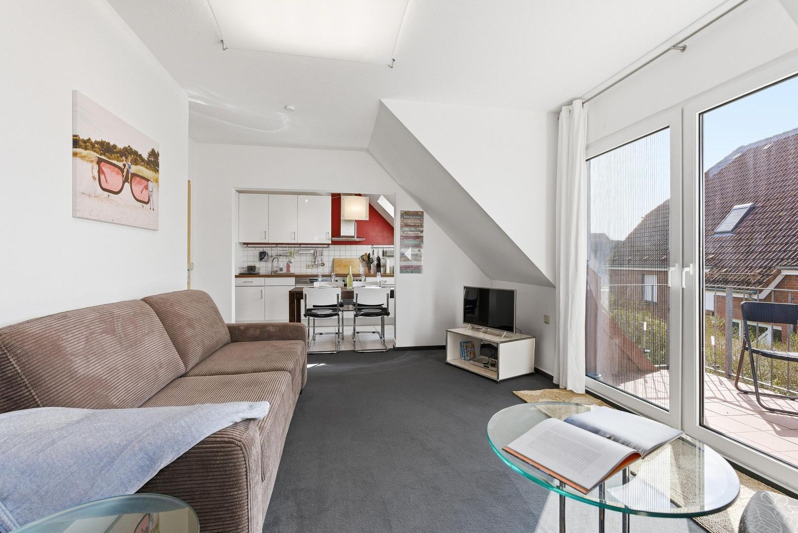 Wohnung mit Sofa, Küche und Balkon. Dachgeschoss mit schrägen Wänden.