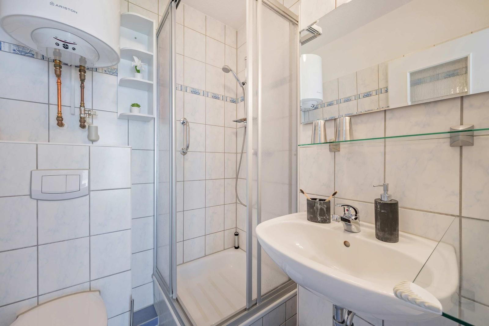 Badezimmer mit Dusche, Waschbecken und Heizung.