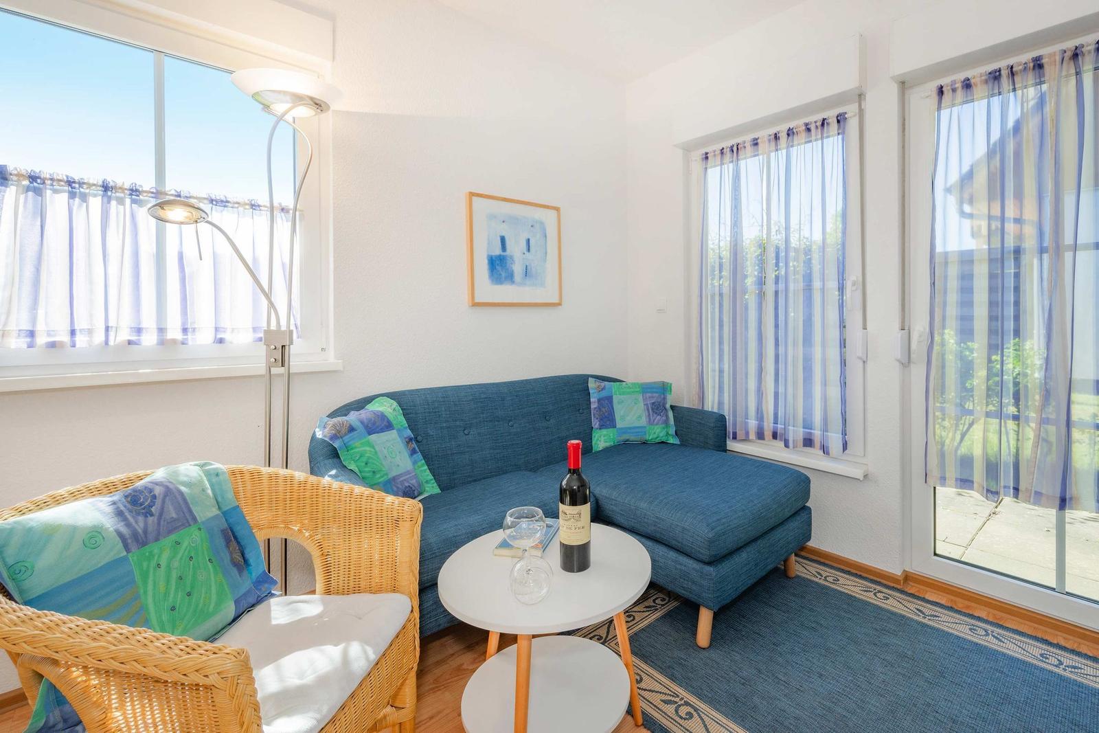 Ein Wohnzimmer mit blauem Sofa, wicker Stuhl und runden Tisch.