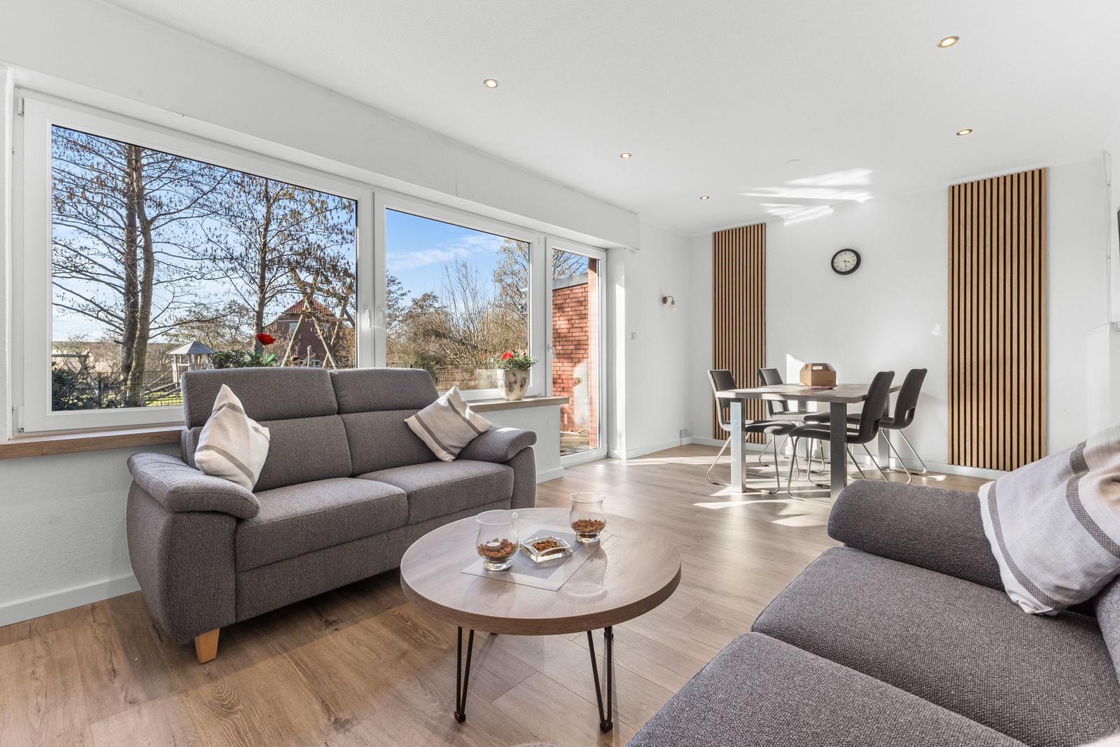 Wohn- und Essbereich mit Sofa, Tisch und Blick auf den Garten.