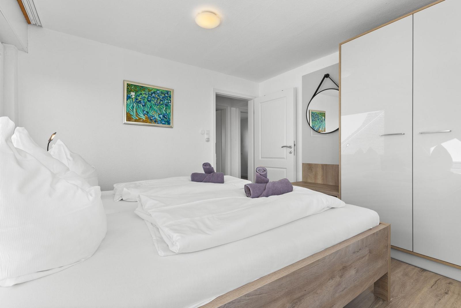 Schlafzimmer mit Doppelbett, Kleiderschrank und Wandbild.