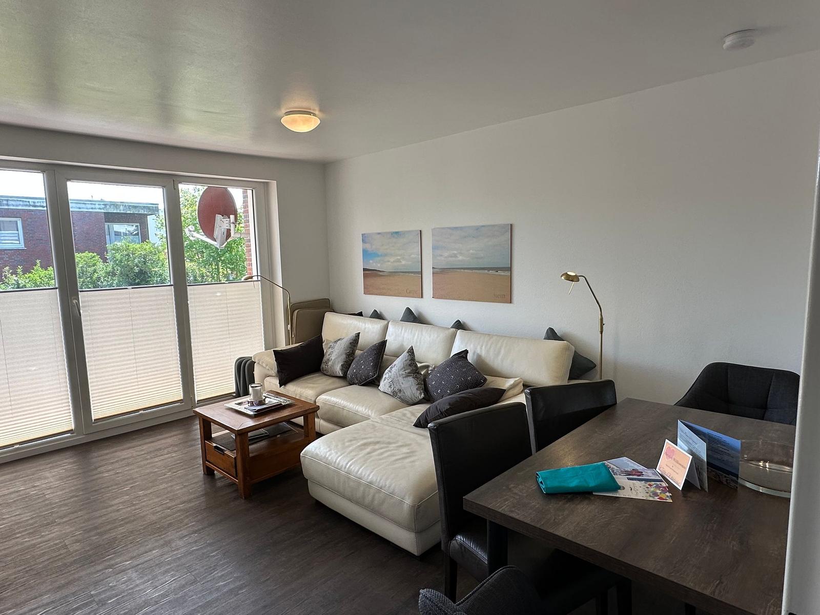 Living area with sofa, dining table, and balcony view.