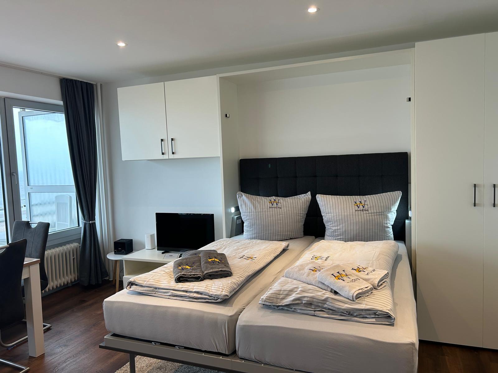 Schlafzimmer mit Doppelbett, Kleiderschrank und Fenster.