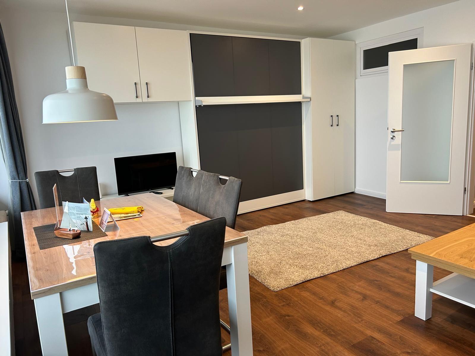 Essbereich mit Tisch, Stühlen und Fernseher. Holzfußboden und Teppich.