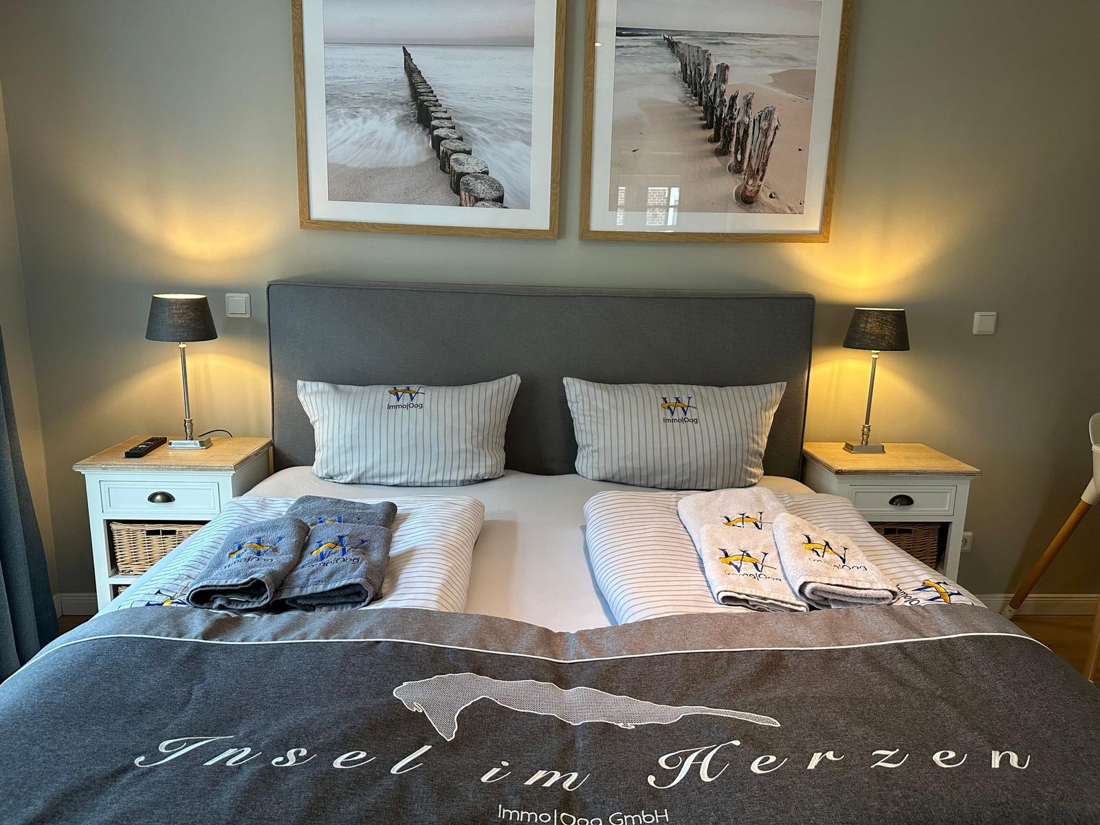 Schlafzimmer mit Bett, zwei Nachttischen und Wandbildern an der Wand.
