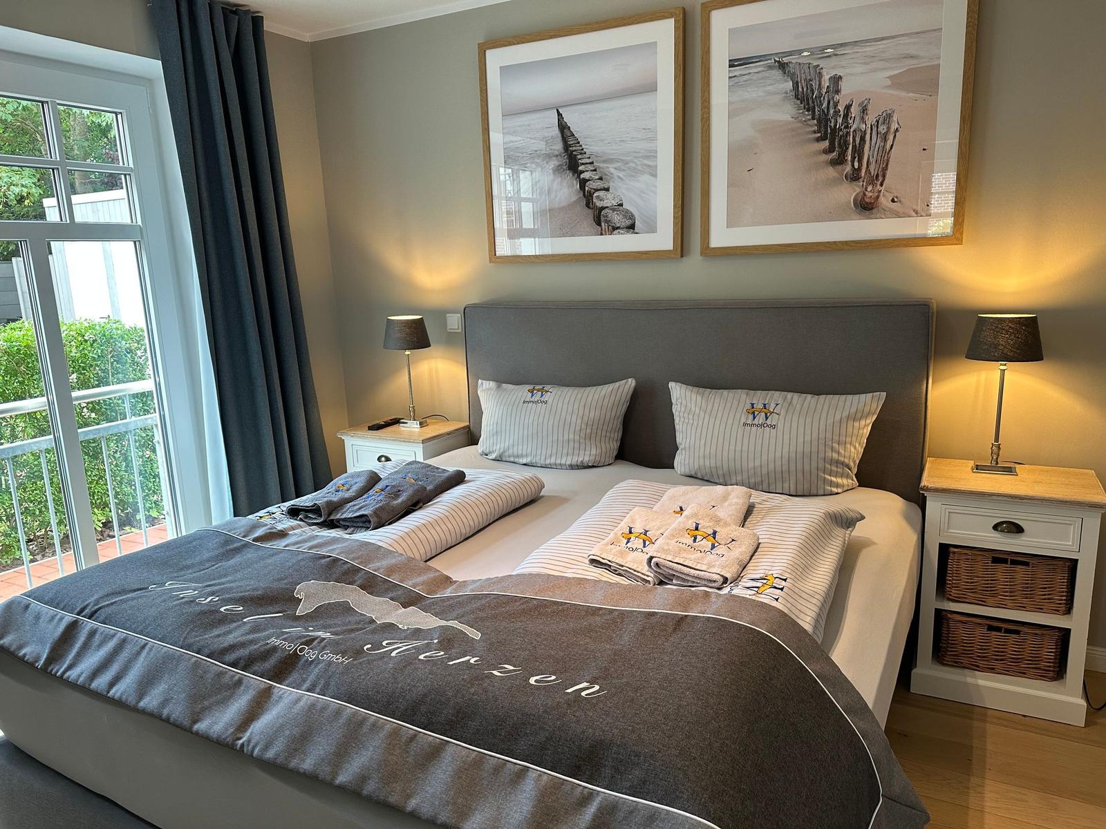 Schlafzimmer mit Doppelbett, zwei Nachttischen und Fenster zum Balkon.
