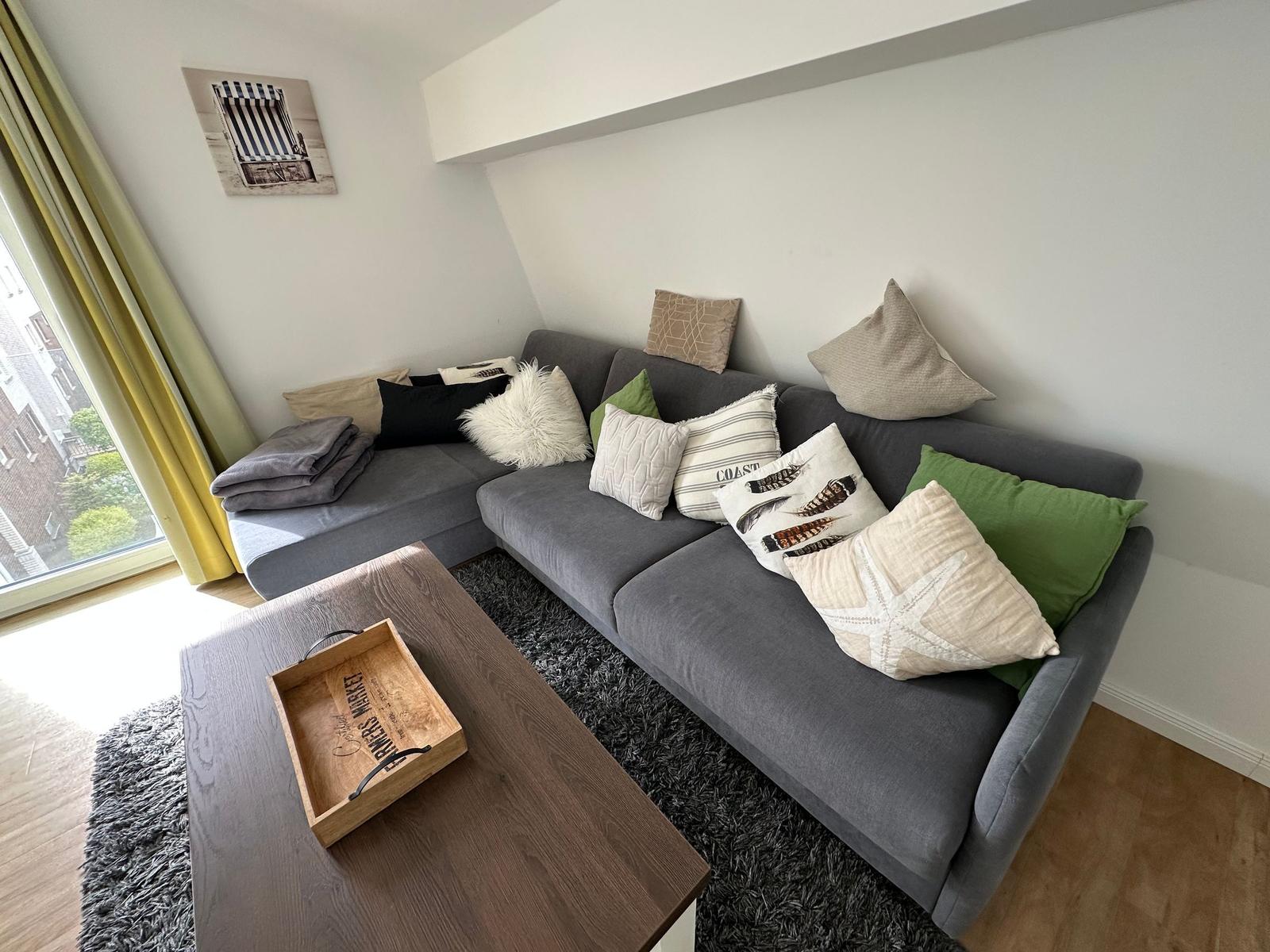 Ein grauer Ecksofa mit Kissen und einem Holztisch im Wohnzimmer.