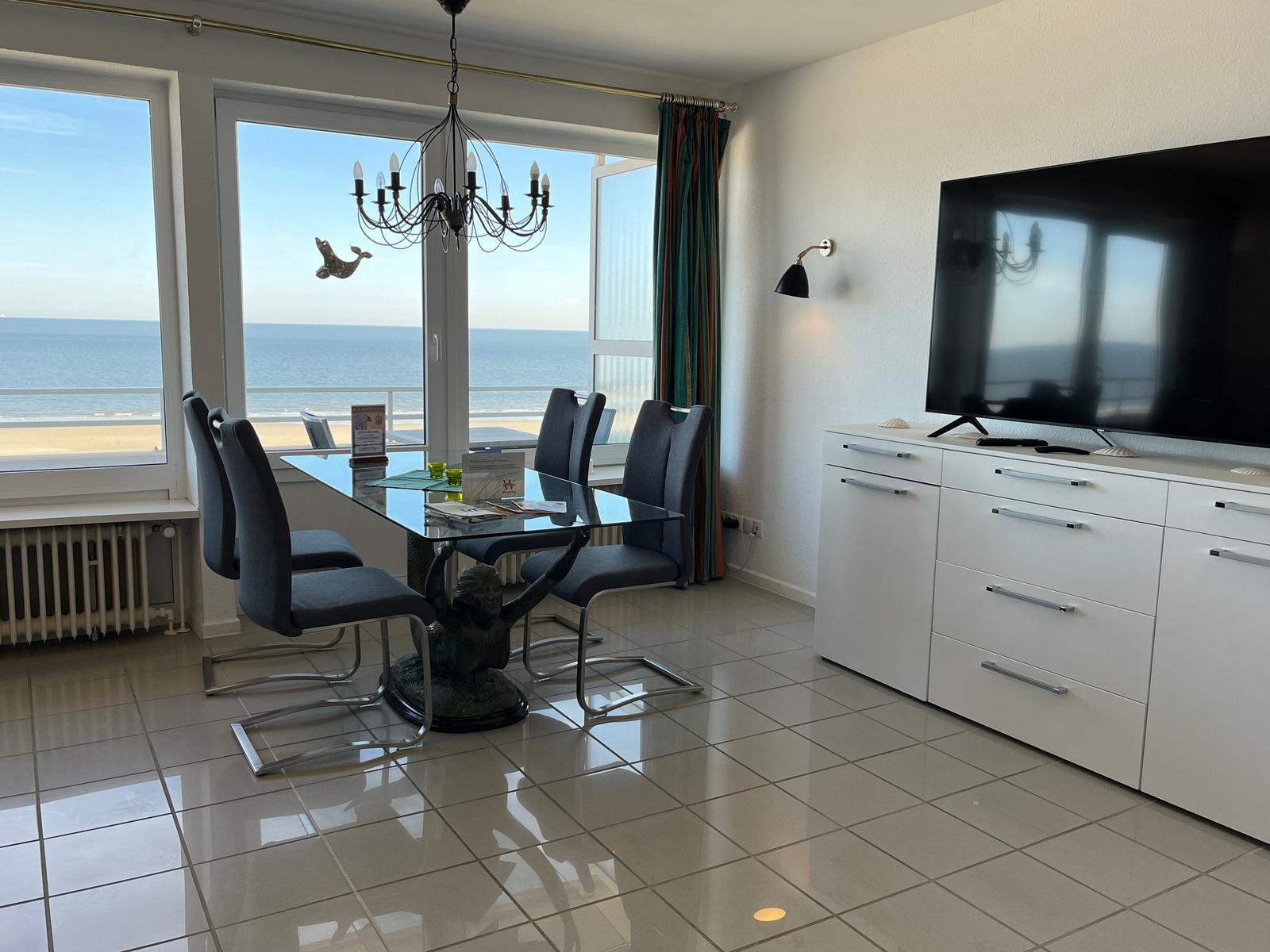 Esszimmer mit Blick aufs Meer, Glas-Tisch, Stühle, TV und Schrank.