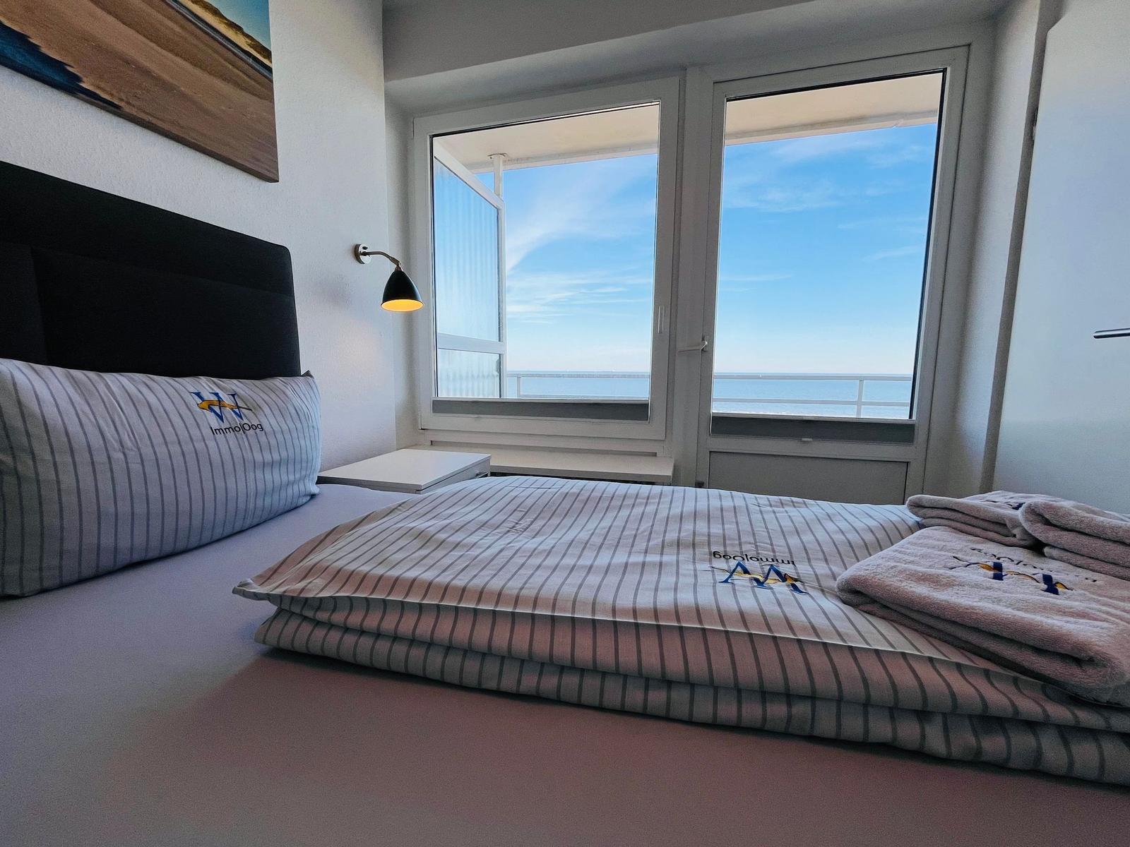 Schlafzimmer mit Blick aufs Meer. Bett mit Bettwäsche und Handtücher.