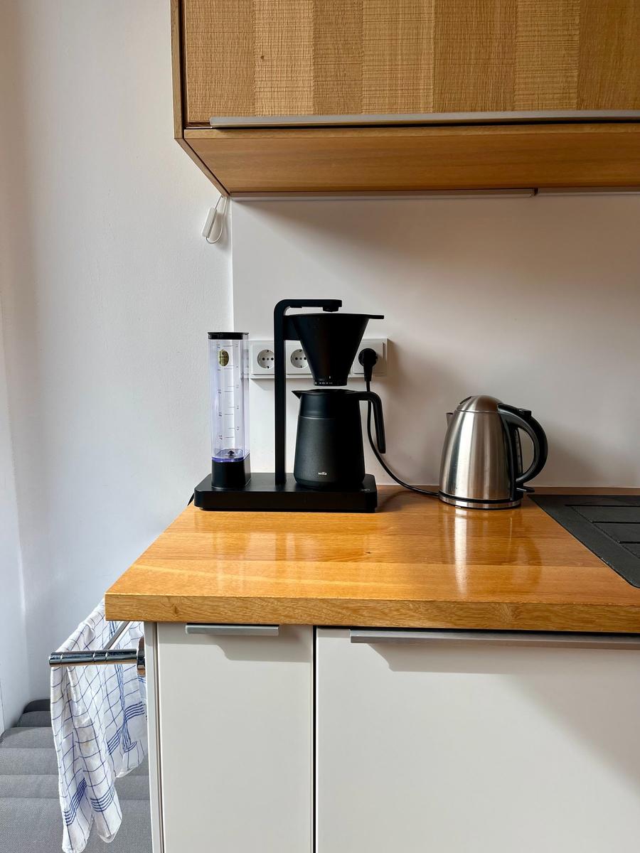 Küchenzeile mit Kaffeemaschine, Wasserkocher und Holzoberfläche.