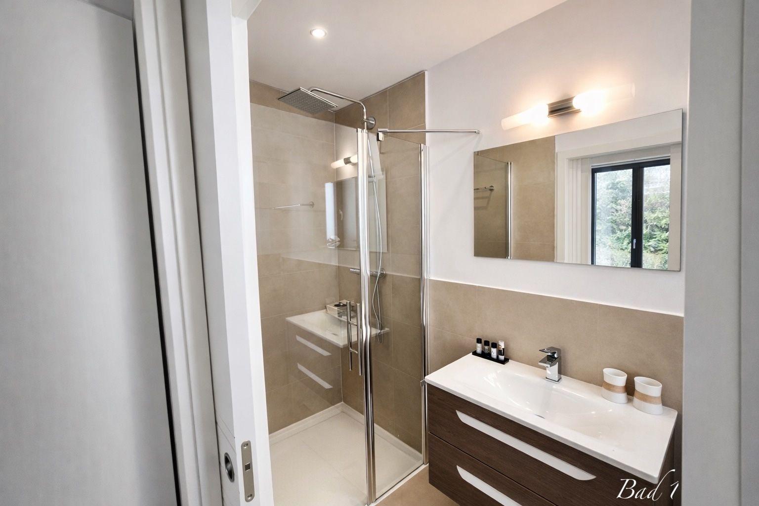 Badezimmer mit Dusche, Waschbecken und Spiegel