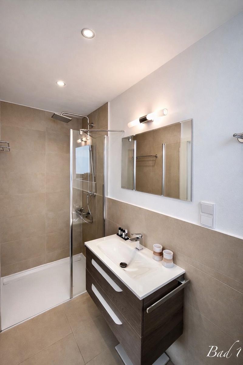 Badezimmer mit Dusche, Waschbecken und Spiegel.