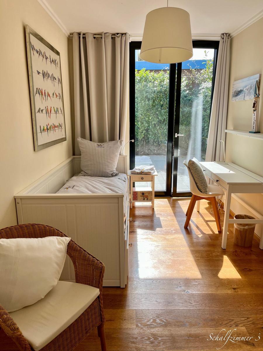 Schlafzimmer mit Bett, Schreibtisch und Blick auf Balkon