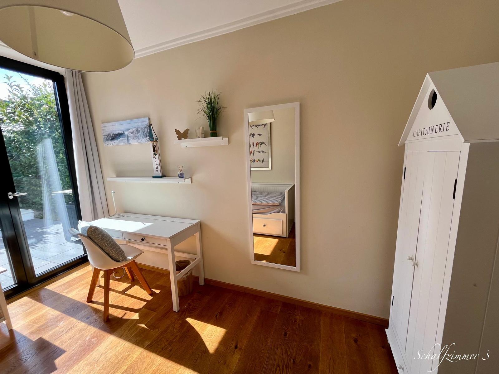Schlafzimmer mit Schreibtisch, Spiegel und Kleiderschrank mit Kapitänschrift.