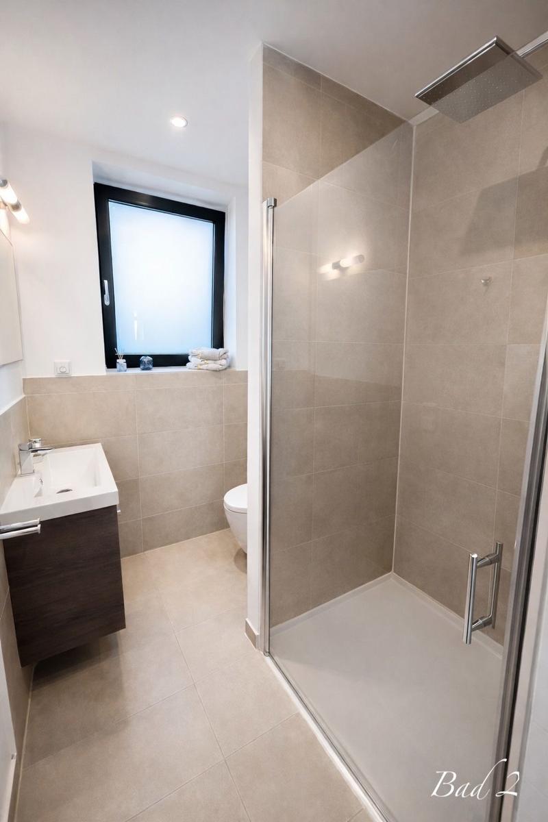 Bad mit Dusche, Waschbecken und Toilette. Fenster mit Rollladen.