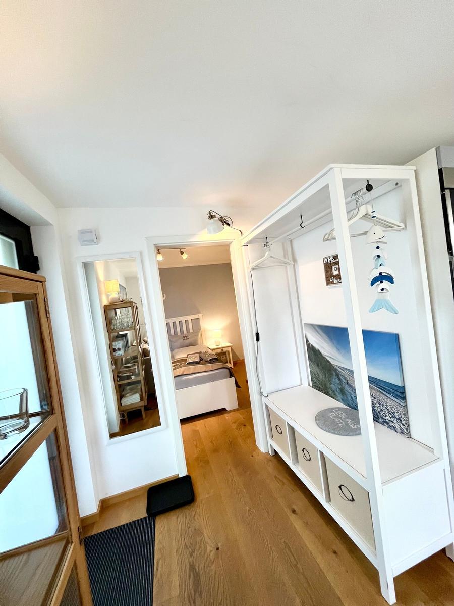 Flur mit Kleiderschrank und Blick in Schlafzimmer mit Bett und Nachttisch.