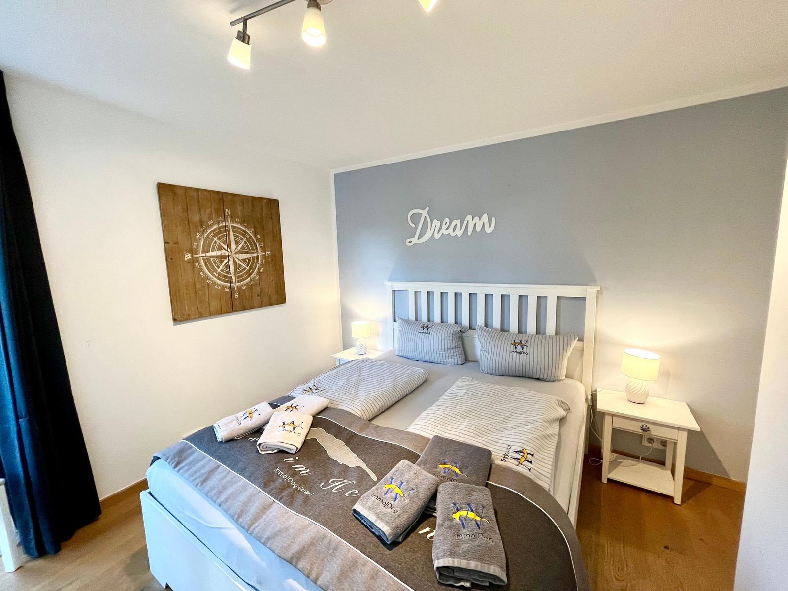 Schlafzimmer mit Bett, Nachttischen und Wanddekoration.