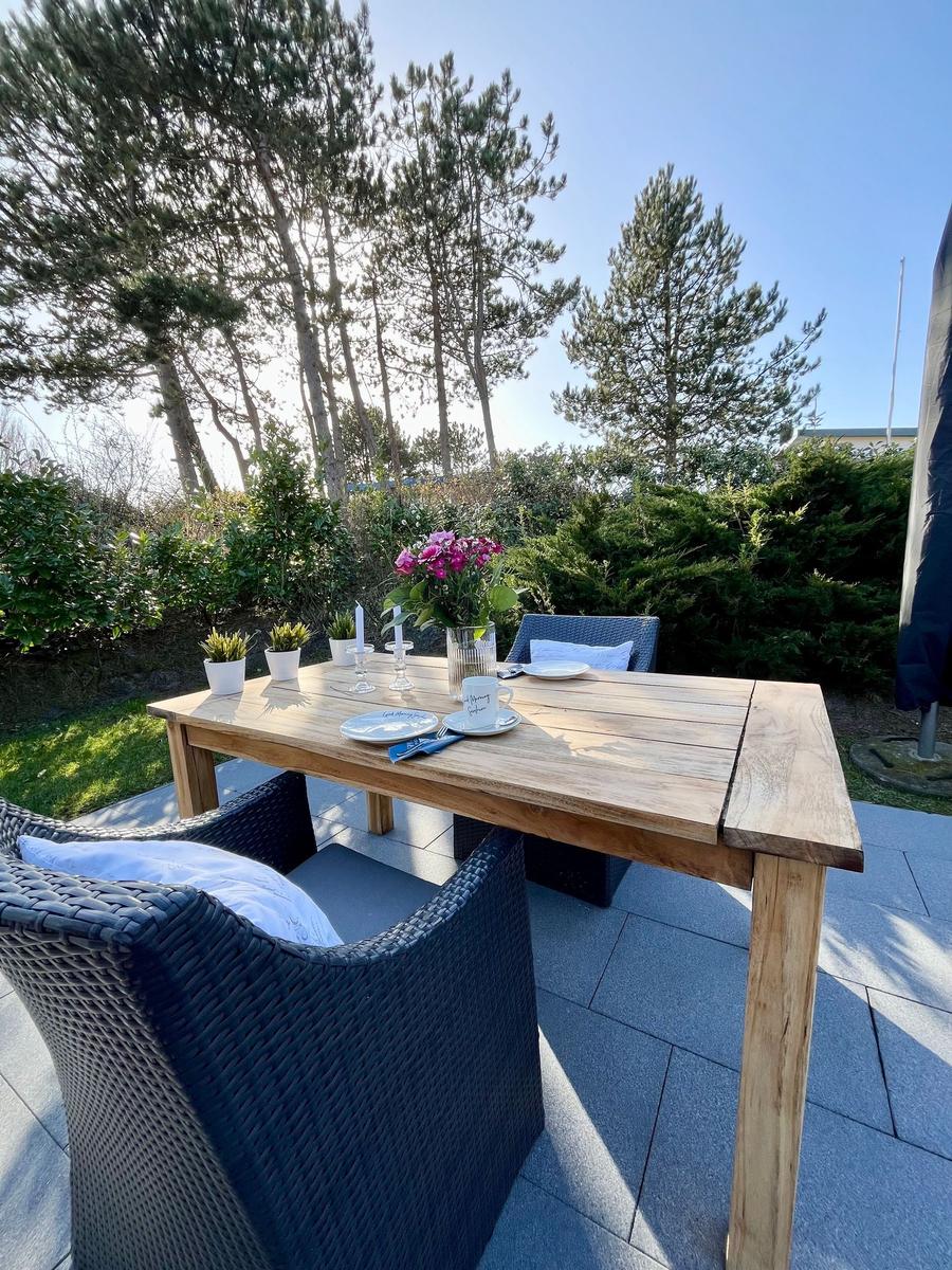 Holztisch mit Stühlen auf Terrasse, Blumen und Tischdekoration