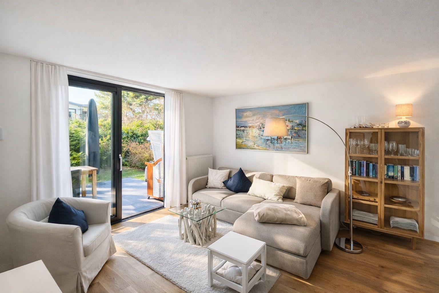 Wohnzimmer mit Sofa, Sessel, Glas-Tisch und Balkon. Wandbild und Bücherregal.