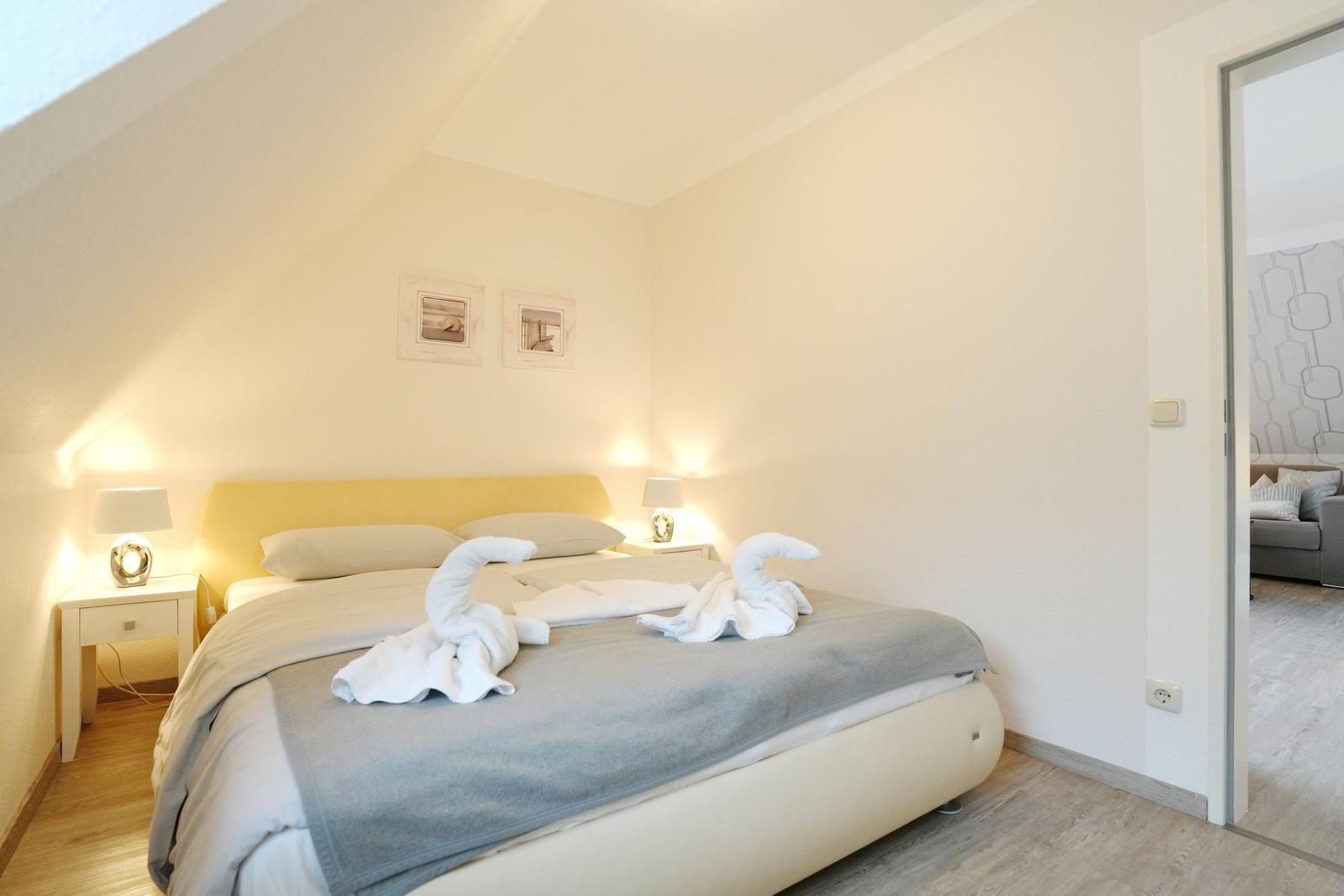 Schlafzimmer mit Bett, zwei Nachttischen und zwei Bildern an der Wand.