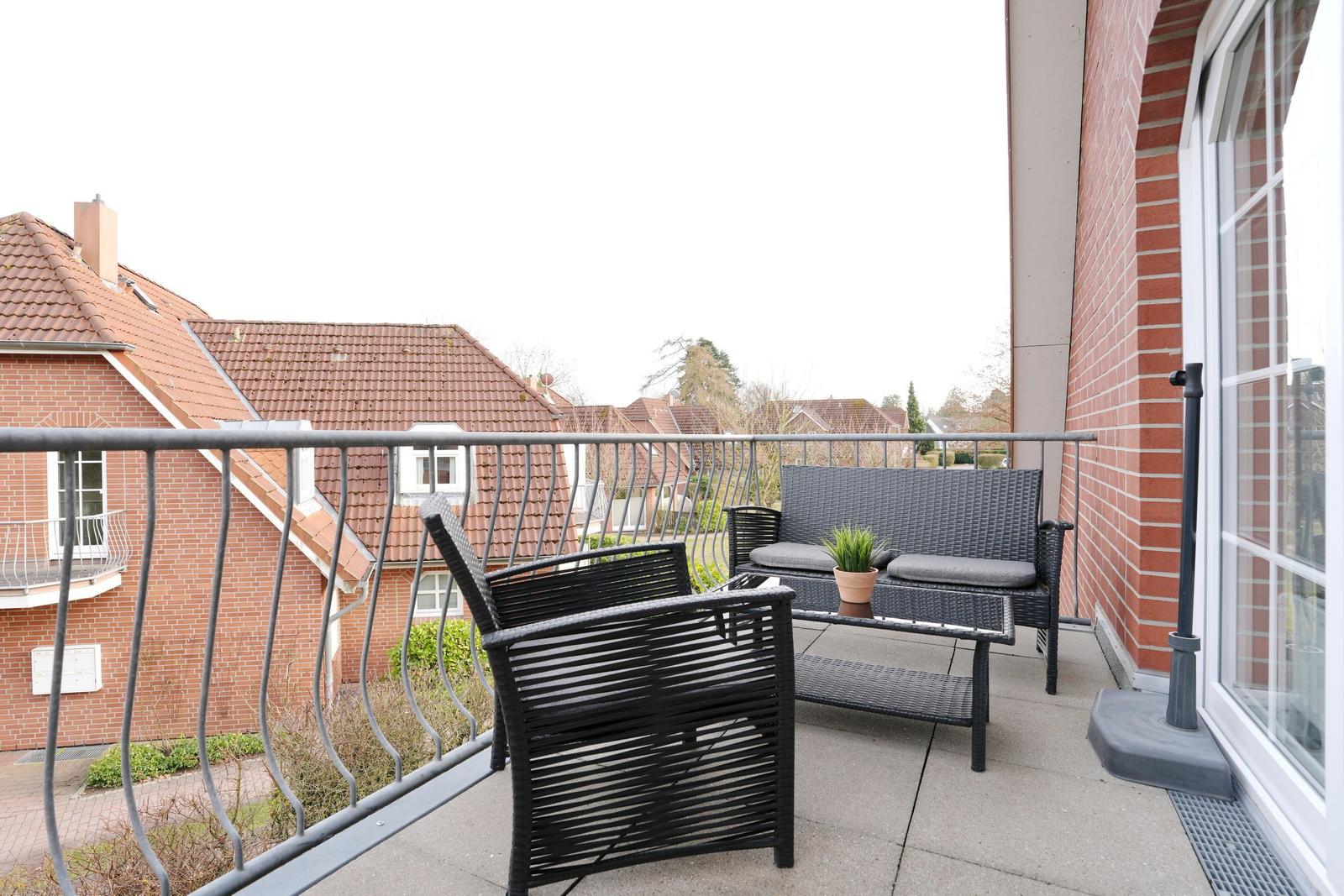 Terrasse mit Sitzgruppe und Pflanze, Blick auf Dächer und Grün.