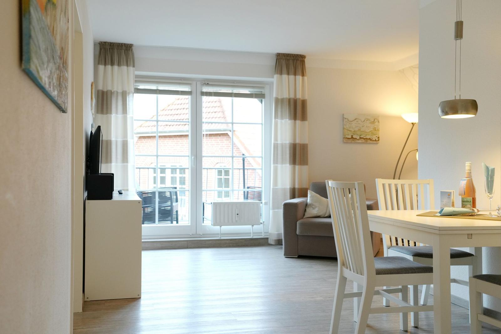 Wohn- und Essbereich mit Fenster, Tisch, Stühlen und Sofa.