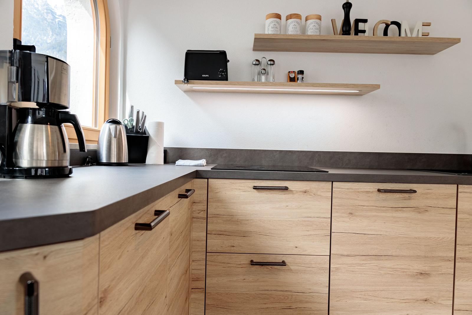 Küche mit Holzschränken, Arbeitsplatte und Küchenutensilien.
