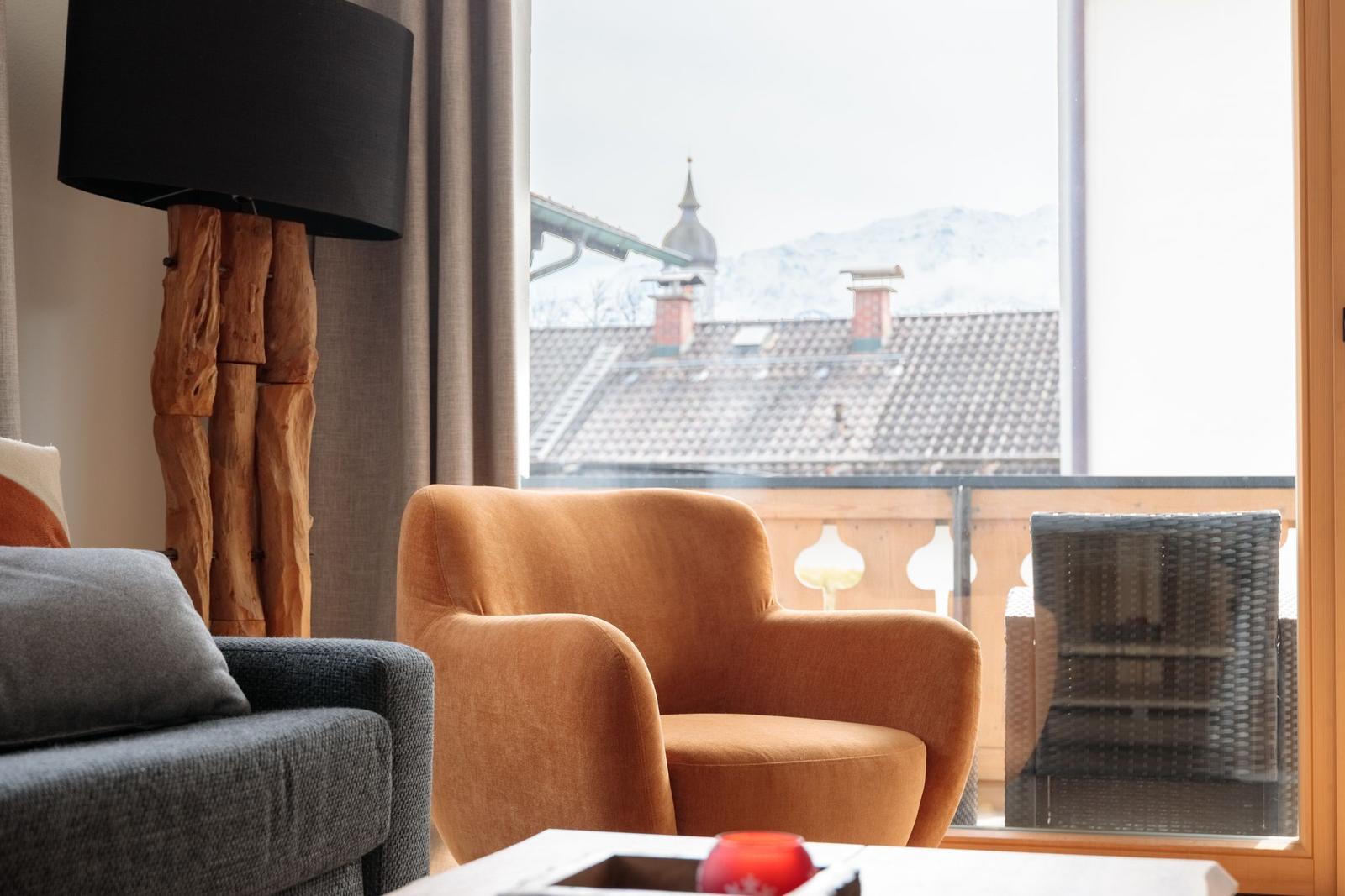 Ein Raum mit Sitzmöbeln und Blick auf Dächer und Berge.