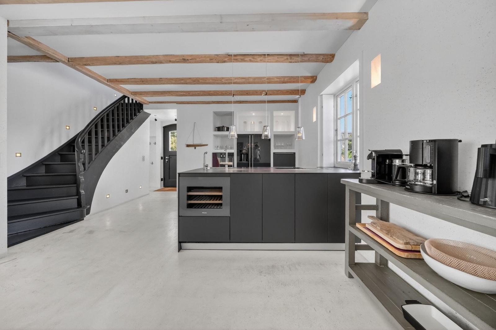 Moderne Küche mit dunklen Schränken und Holzbalken an der Decke.