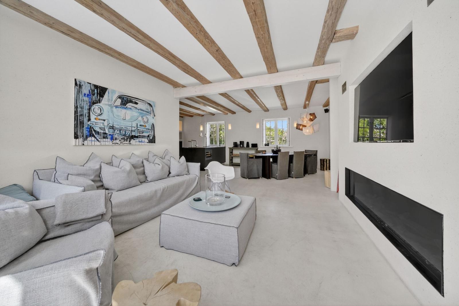 Wohn- und Essbereich mit Sofa, Kamin und Holzbalken an der Decke.