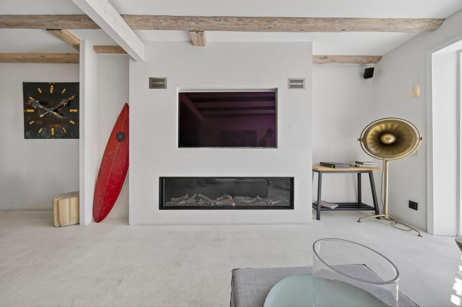 Raum mit Kamin, Fernseher, Surfbrett und goldener Stehlampe.