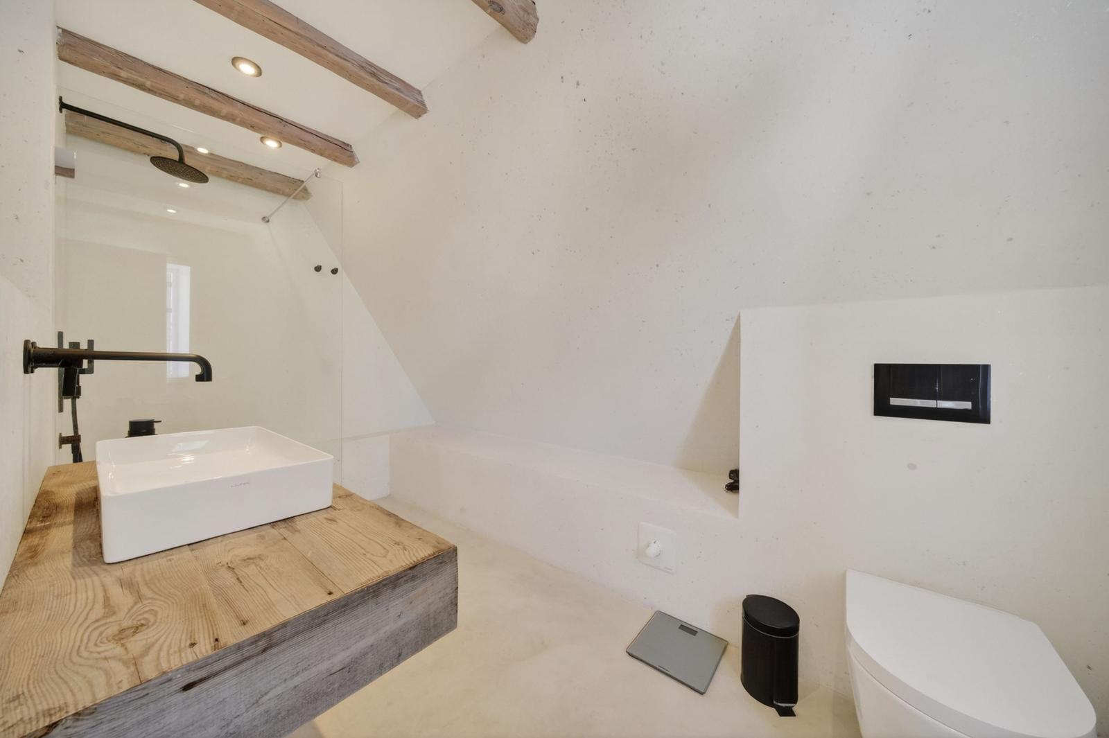 Badezimmer mit Dusche, Waschbecken auf Holz und Toilette.