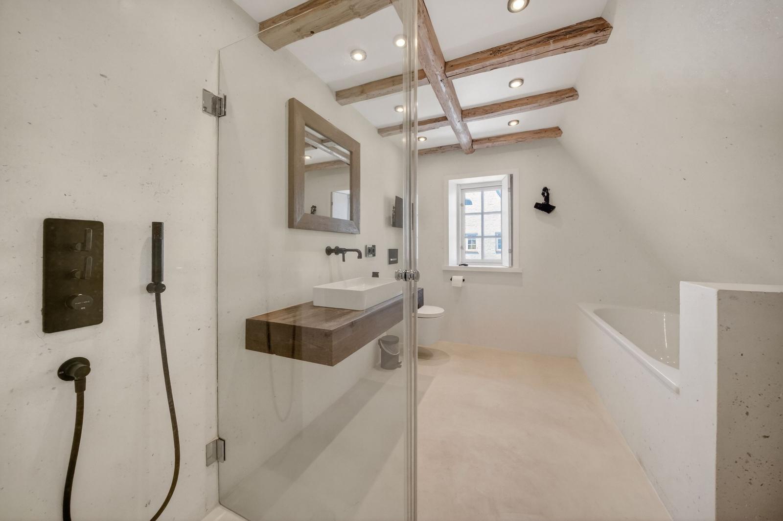 Bad mit Dusche, Waschbecken und Badewanne unter Holzbalken