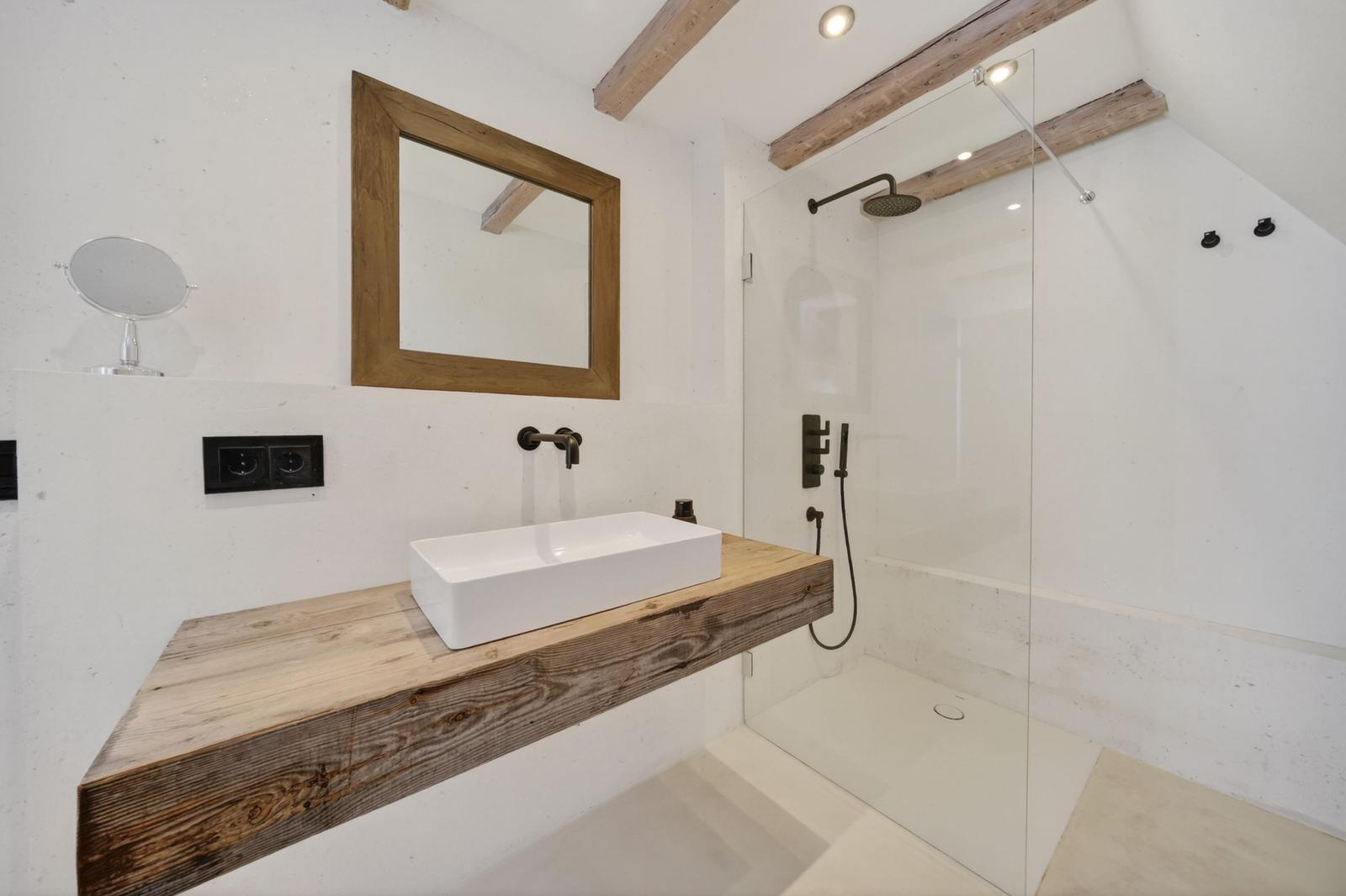 Bad mit Dusche, Waschtisch auf Holzkonsole und Spiegel mit Holzrahmen.