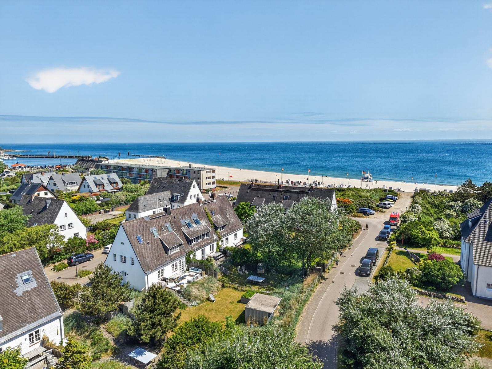 Haus mit Blick auf Strand und Meer. Umgeben von Grünflächen und gepflasterten Straßen.