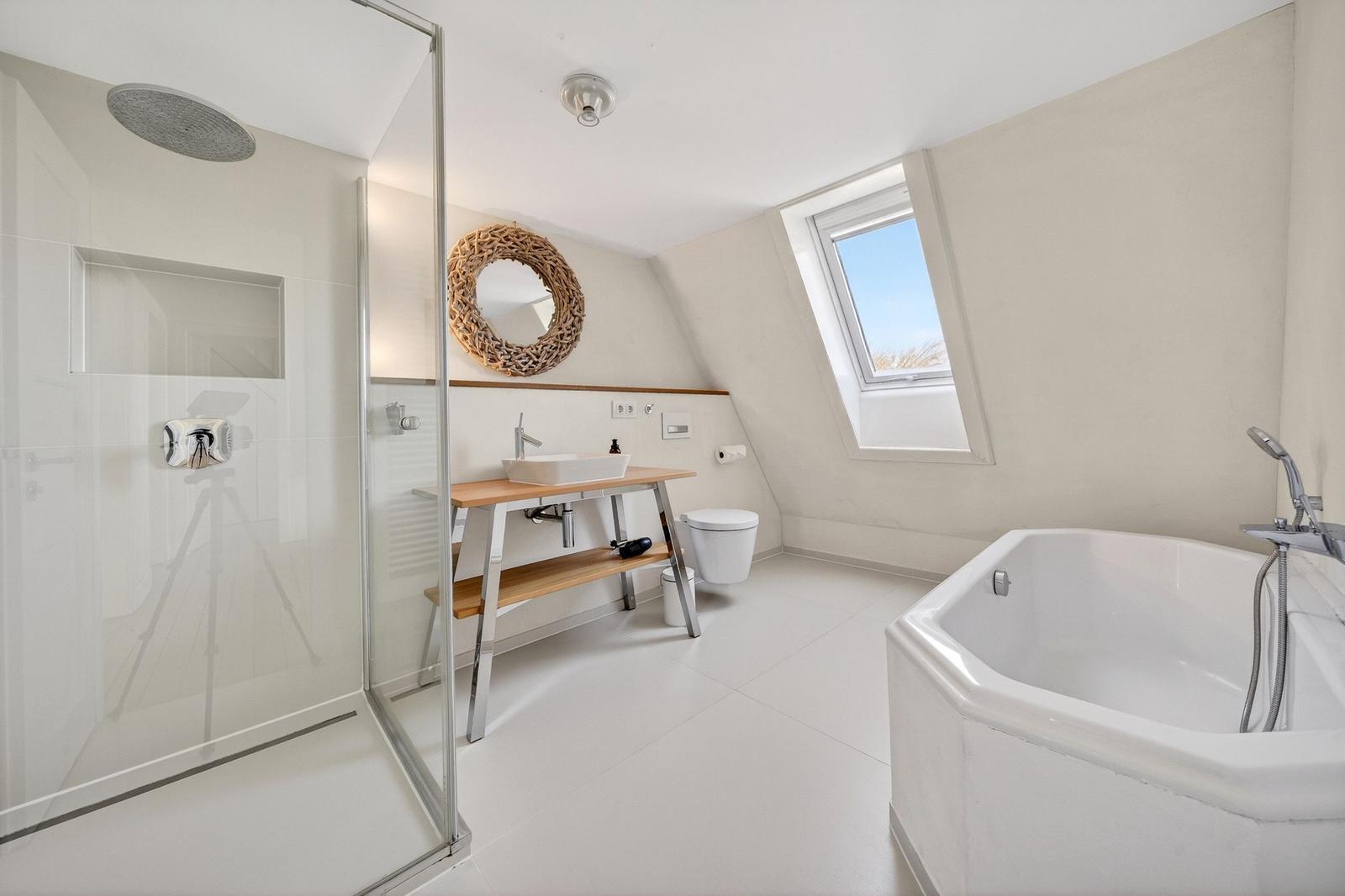 Dusche, Badewanne und Waschtisch in einem hellen Badezimmer mit Dachfenster.