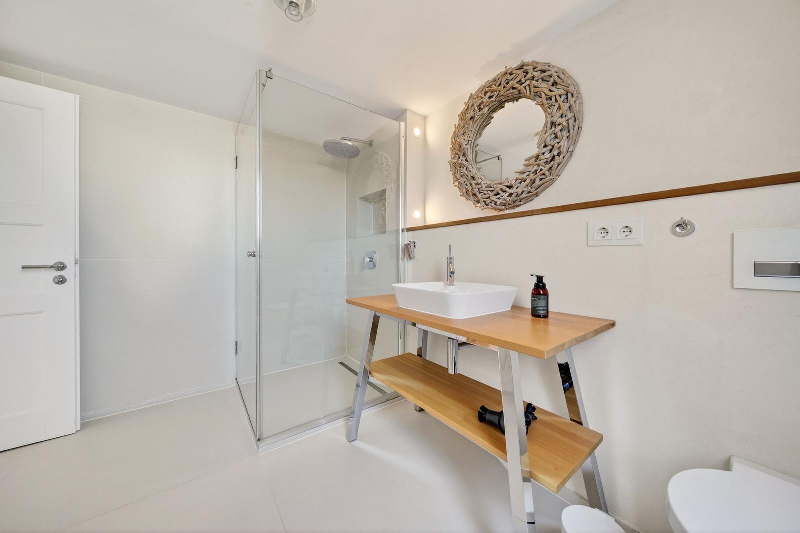 Badezimmer mit Dusche, Waschtisch und Spiegel