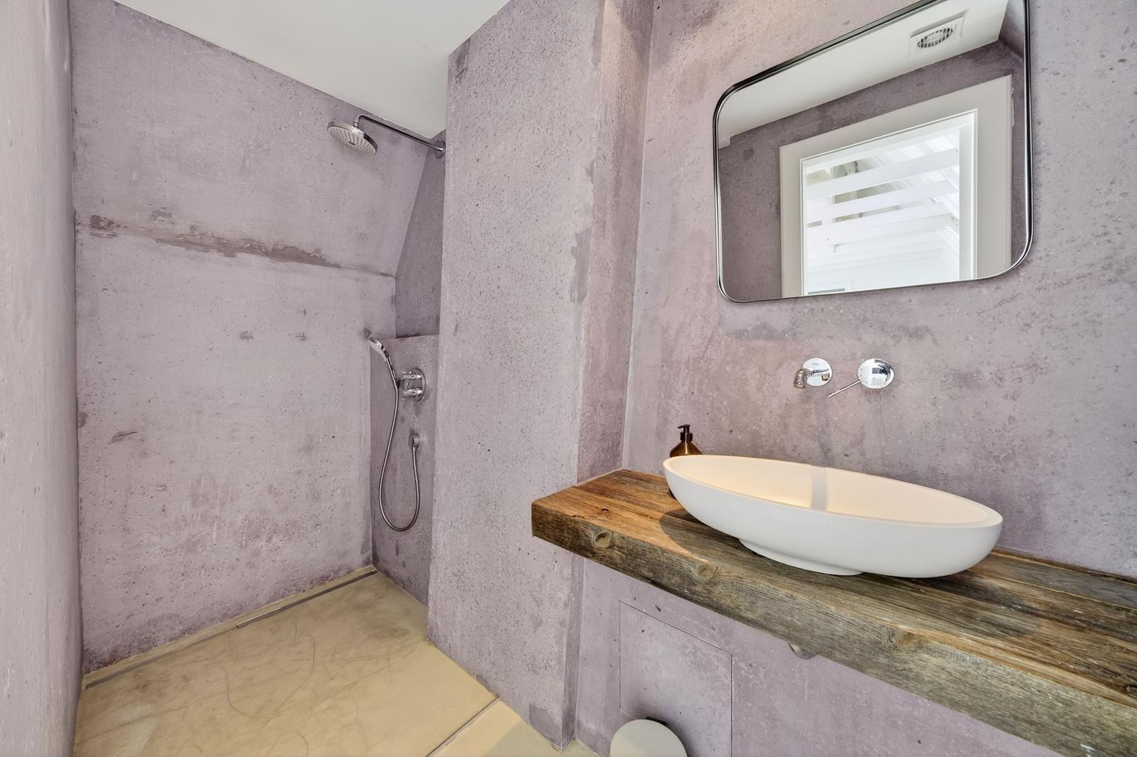 Dusche mit Duschbrause und Waschbecken auf Holzkonsole