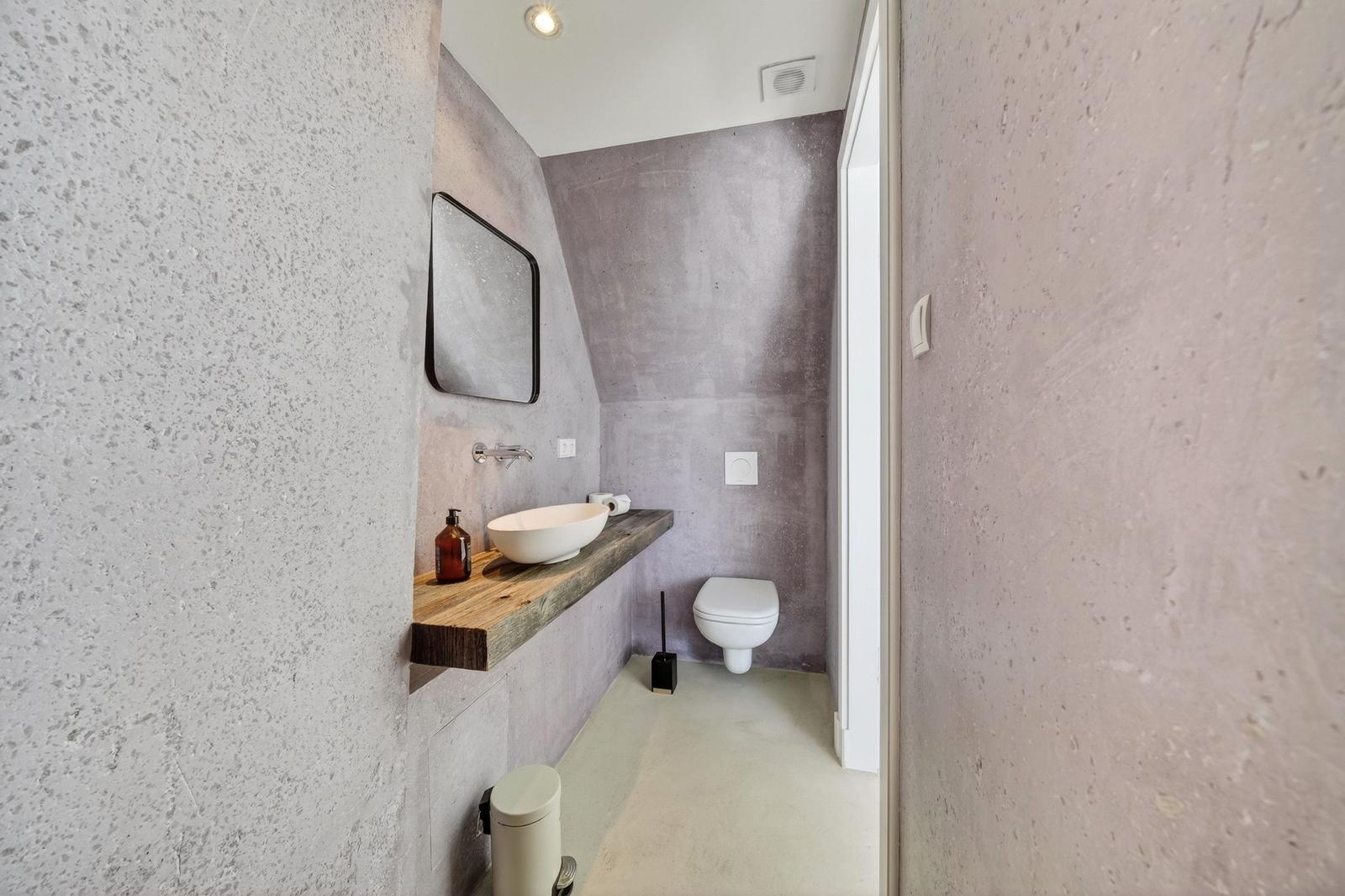 Badezimmer mit Waschbecken auf Holzplatte, Spiegel und Toilette.