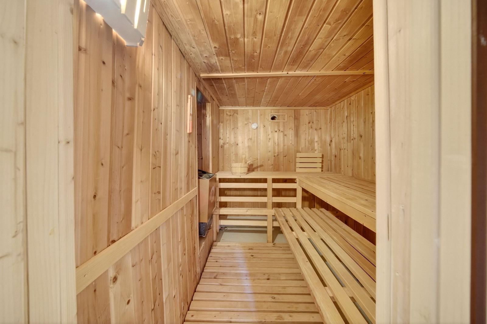 Holzsauna mit Bänken und Heizung. Raum mit Holzwänden und -decke.