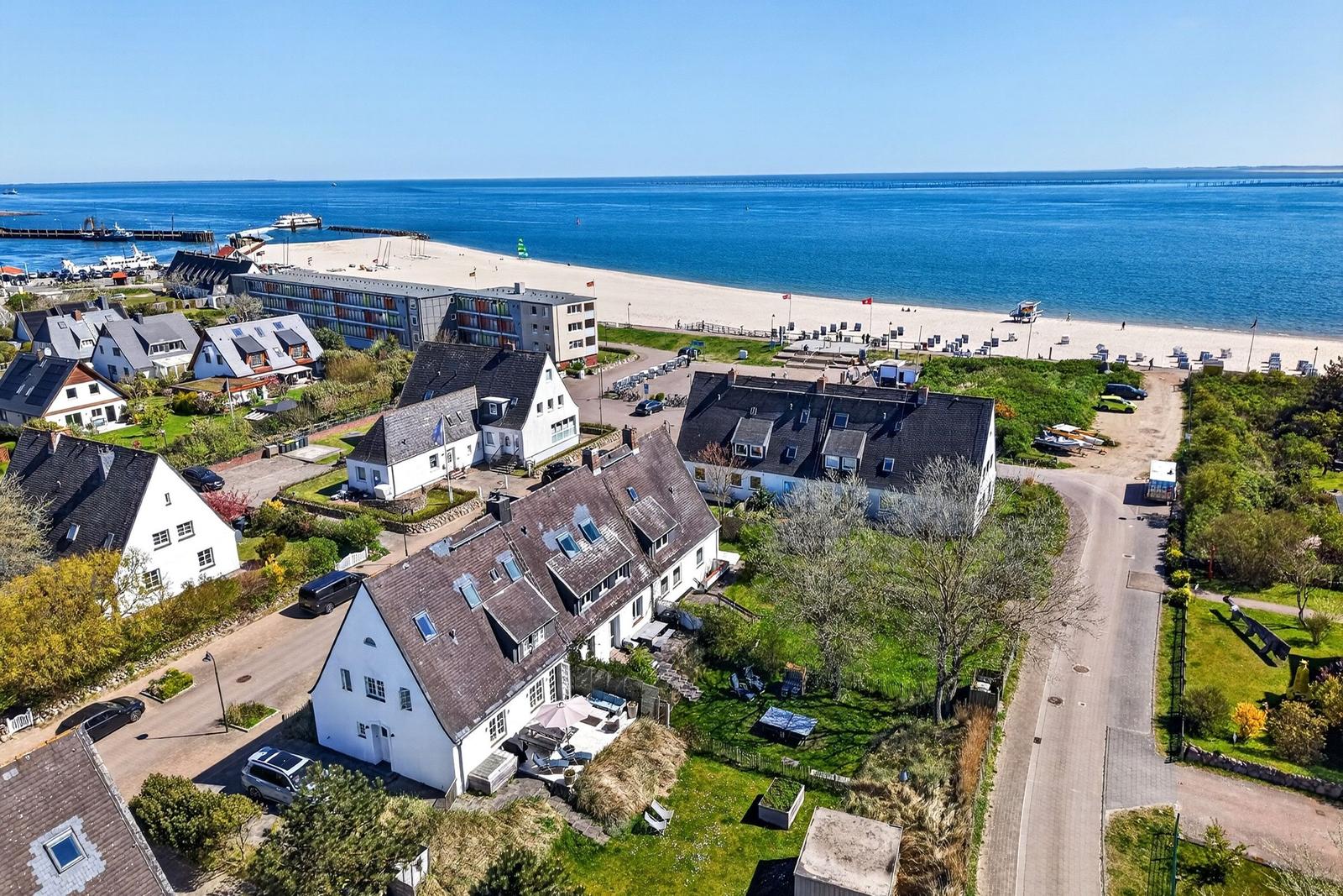Haus mit Garten, Strand und See im Hintergrund.